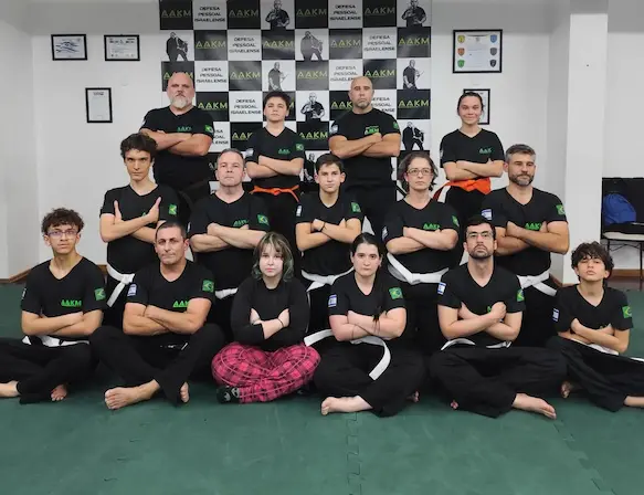 Turma unida de alunos e alunas de diversas idades com Mestre Adriano Almeida após aula presencial na academia de Krav Maga AAKM em Porto Alegre, RS.